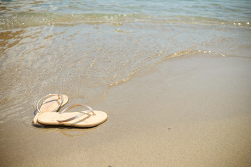Beach pink flip-flops on a light sand. Texture of light sand. The concept of a beach holiday....