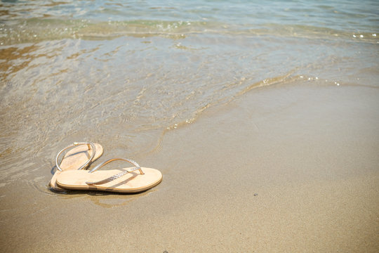 Beach pink flip-flops on a light sand. Texture of light sand. The concept of a beach holiday. Summer shoes. Fashion slaps, Sandals,Summer vacation concept .Copy space