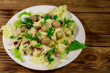 Potato salad with marinated mushrooms, eggs, red onion and mayonnaise on wooden table