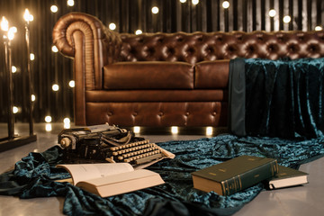 close up photo of a typewriter on a piece of newspaper and dark blue velvet fabric on the floor...