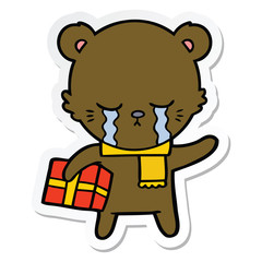 sticker of a crying cartoon bear with present