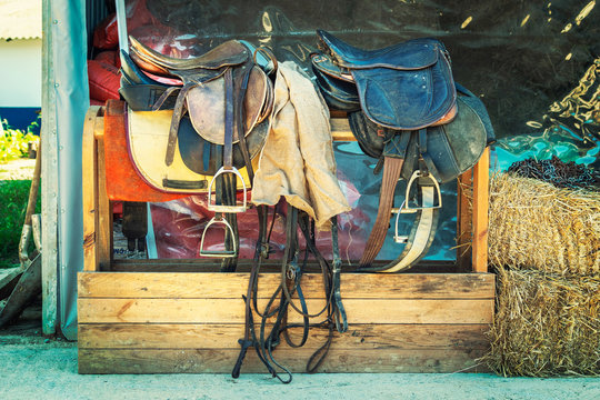 Old Leather horse saddle displayed on a stand In front of the stable - Image