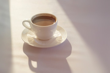 White Cup with black Turkish coffee on white tablecloth