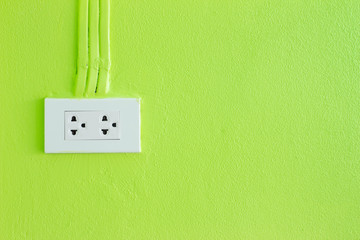 Electric plug on green wall with copy space for text message or artwork.