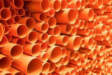 orange PVC pipes stacked in construction site