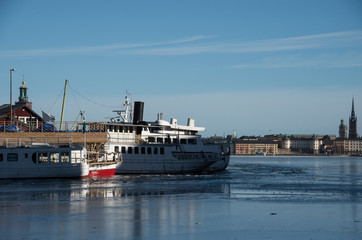 An sunny early spring day in Stockholm, view over a pier with boats and Town City Hall at lake M&auml;laren