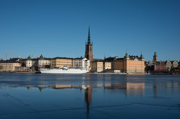 Obraz premium An sunny early spring day in Stockholm, view over a pier with boats and Town City Hall at lake Mälaren
