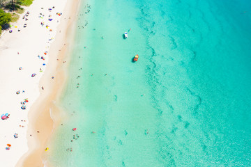View from above, aerial view of a beautiful tropical beach with white sand, turquoise clear water and people sunbathing, Surin beach, Phuket, Thailand.