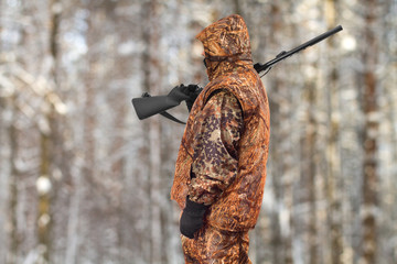 hunter with a gun on his shoulder in the winter forest