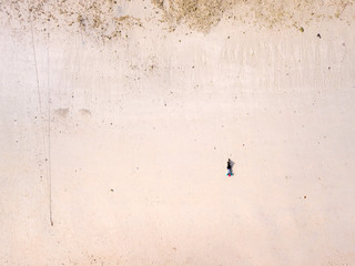 Aerial view of women in swiming suit reclining on the white sand beach