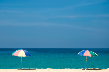 Raise an two beach umbrella on beautiful sunny day, clear sea and sky on background