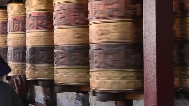 Prayer wheels in Jokhang temple. The characters (in Newari language & Tibetan) on the wheels are the mantras "Om Mani Padme Hum", each word means "sacred, bead, lotus flower, spirit of enlightenment"