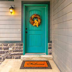 Blue green front door with a welcoming wreath © Jason