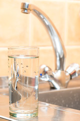 a glass of clean drinking water on the background of the kitchen tap