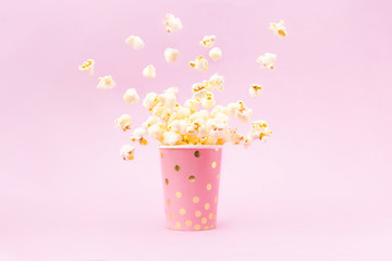 Flying Popcorn in a bright glass and on a pink background.