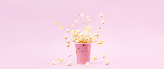 Flying Popcorn in a bright glass and on a pink background.
