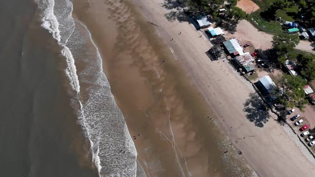 Aerial footage view of  Ocean Waves Crashing On Beach With People Walking By On Beautiful Beach in 4K resolution 