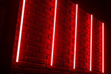 Red neon lines on brick wall in night club.