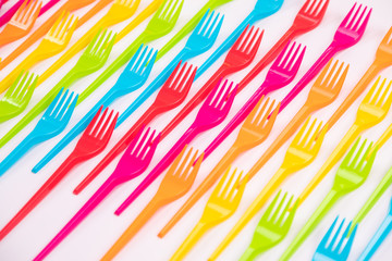 Many color plastic forks on a bright background