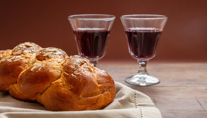 Challah bread with two glasses of red wine on wooden table