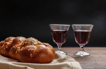 Challah bread with two glasses of red wine on wooden table