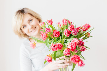 Happy attractive middle-aged blonde woman with a bouquet of red pink white tulips