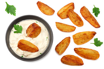 Fried potato wedges with garlic sauce in black bowl isolated on white background. top view.