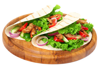 Tortilla wrap with fried chicken meat and vegetables on wooden board isolated on white background
