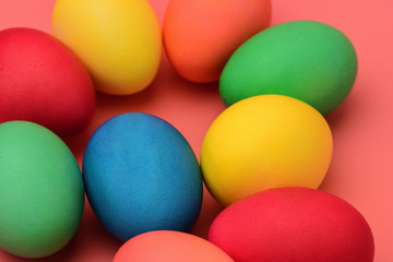 .Colorful Easter eggs lie on a coral background. Horizontal photography.