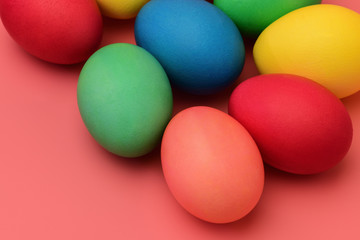 Colorful Easter eggs lie on a coral background. Horizontal photography.