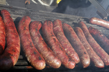 Grilled sausages on bbq. Roasted meat sausages on a barbeque. Fast food outdoor on a grill. Natural light. 