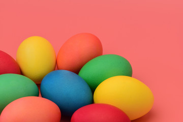 Colorful Easter eggs lie on a coral background. Horizontal photography