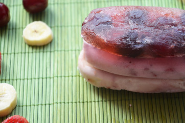 Homemade strawberry cherry banana blueberry ice cream or popsicles decorated green mint leaves on teal rustic table, frozen fruit juice, vintage style, top view