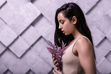 Fototapeta premium Profile studio photo of long-haired brunette girl cuddling lilac flowers