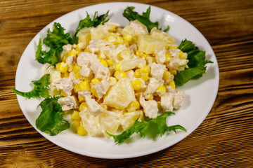 Festive salad with chicken breast, sweet corn, canned pineapple and mayonnaise on wooden table