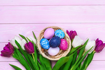 Easter eggs in a nest and tulips on wooden planks