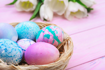 Easter background with colorful eggs and  tulips over pink wood. Top view with copy space