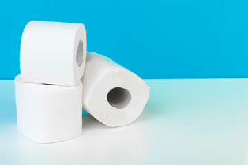 Three toilet paper rolls isolated on white table with blue background