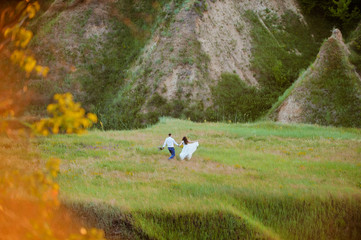 A man and a girl run across the meadow against the backdrop of the mountains.