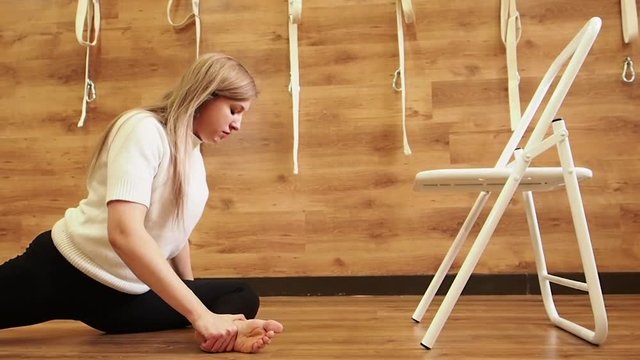 Yoga practitioner doing exercises with a chair that is used as a prop to perform various assan. Flexibility concept. Slow Motion