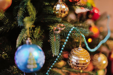 Obraz na płótnie Canvas Wedding rings on decorated Christmas tree