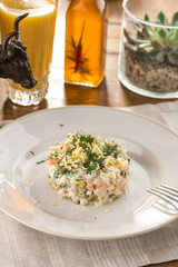 Traditional Russian salad Olivier with egg on top on on wooden table