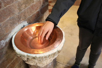 hand of the boy and the copper stew cup with the holy water