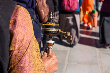 An old woman prayer with her mani wheel (hand prayer wheel) in Jokhang temple, Lhasa, Tibet, China.