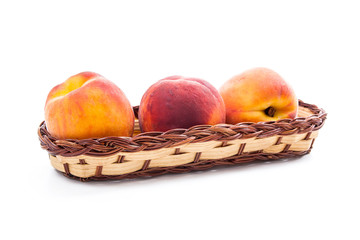 Group of ripe peach fruit in basket isolated on white background.
