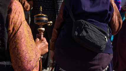 An old woman prayer with her mani wheel (hand prayer wheel) in Jokhang temple, Lhasa, Tibet, China.