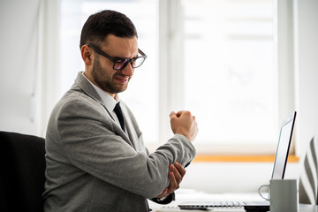 Young businessman is having pain in his elbow.