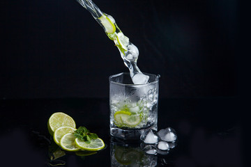 Summer cocktail mojito with splash on black background..