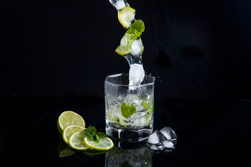 Summer cocktail mojito with splash on black background..