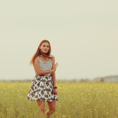 Portrait of a beautiful girl in a field with yellow flowers, summer, sunset